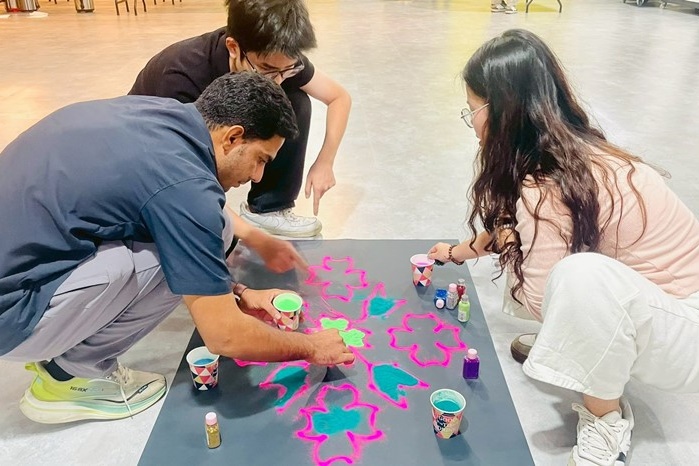 Student participants conveyed light and blessings through vibrant patterns in the 'Rangoli Painting Competition'.